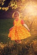 Little girl in a beautiful dress in the rays of the evening sun