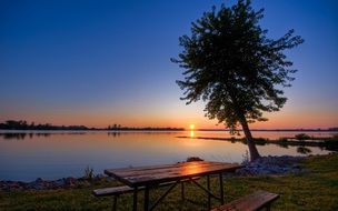 wooden table and benches by the lake on the background of a beautiful sunset