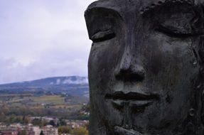 female face sculpture at scenic rural landscape, italy