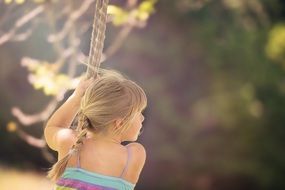 girl stands with her back and holds on to the rope on a blurred background