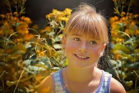 Little girl with a smile on a background of yellow flowers