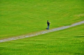 man standing on green grass at road