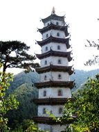 white tower of a buddhist temple among green trees