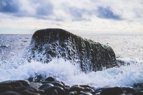 splashing water on a large rock on the coast