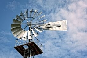 metal pinwheel against the sky with white clouds