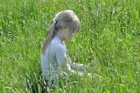 girl with white hare sits on a green meadow
