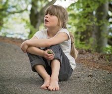 A girl with long hair is sitting on the road