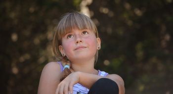 a girl with a smile sits on the ground