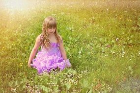 Little girl in a beautiful dress with long curly hair amid the meadow