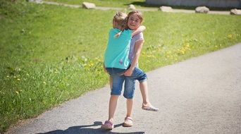 girl carries her sister in her arms