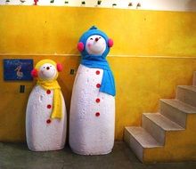 Snowman sculptures near the yellow wall