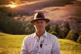 man in hat on the hill at sunset