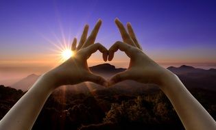 sign of love from hands on sunset background