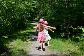 two girls coming away by road in trees