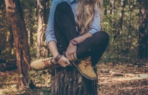 A girl sits on a stump in the forest