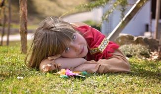 Little girl with long hair lies on nature