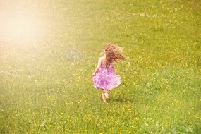 Little girl in a beautiful purple dress running through the meadow