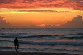 silhouette of a surfer on the beach at sunrise