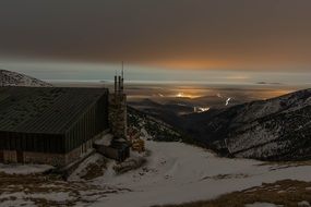 big hut on a snowy mountain at dusk