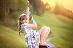 Little girl is playing on a swing in the nature