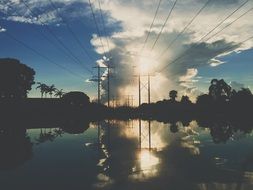 landscape of power lines are reflected in the water at dusk