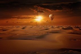 hot air balloon flies over the desert against the backdrop of a golden sunset