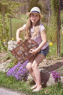 A little girl in a hat and barefoot with luggage in the park