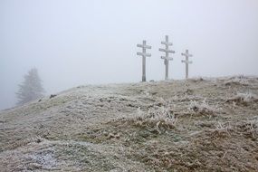 three crosses on a mountain in a haze