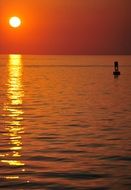 the red sun is reflected on the water