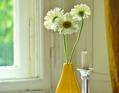 daisies in a yellow vase in the house