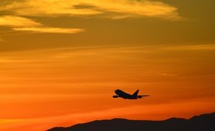 flying airplane silhouette at red sky