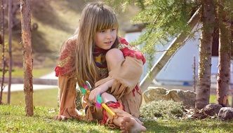 A little girl with long hair plays in an Indian costume