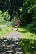 Two little girls running around the forest trail