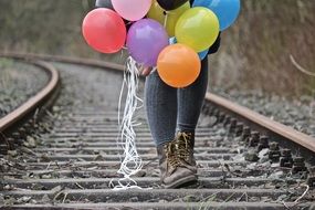 child with balloons on the rails