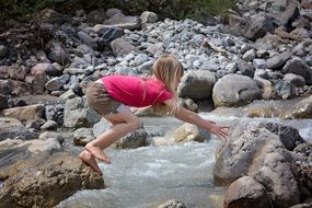 Little girl barefoot playing on rocks near the creek