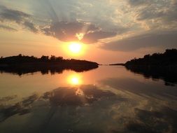 Sunset on the cloudy sky over the lake