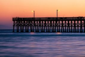 lampposts on the sea pier on the background of pink sunset