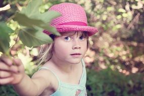 Portrait of a little girl in a pink hat on a blurred background