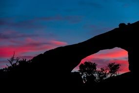 sandstone arch against a pink sunset