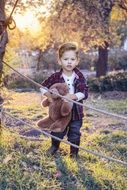 child with a soft toy among the autumn landscape