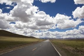 Beautiful, free straight road among the colorful fields under white fluffy clouds