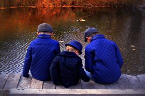 Boys are sitting near the river in the autumn