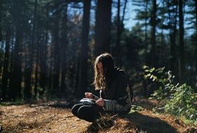 girl reads a book in the forest
