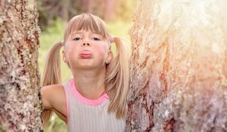 Little girl with blond long hair with a grimace