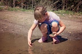 blonde girl sitting in water puddle