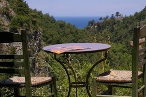 Beautiful panorama of the green plants on the mountains from the place with table and chairs in Samos, Greece