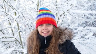 girl in a striped hat and jacket outside in winter