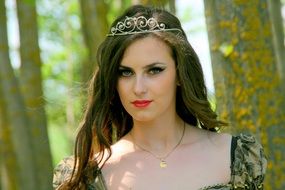 Portrait of a girl with a crown on her head in the forest