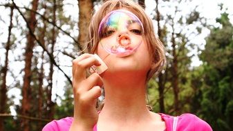 girl blowing soap bubbles on nature