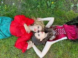 two girls in suits lie on the grass
